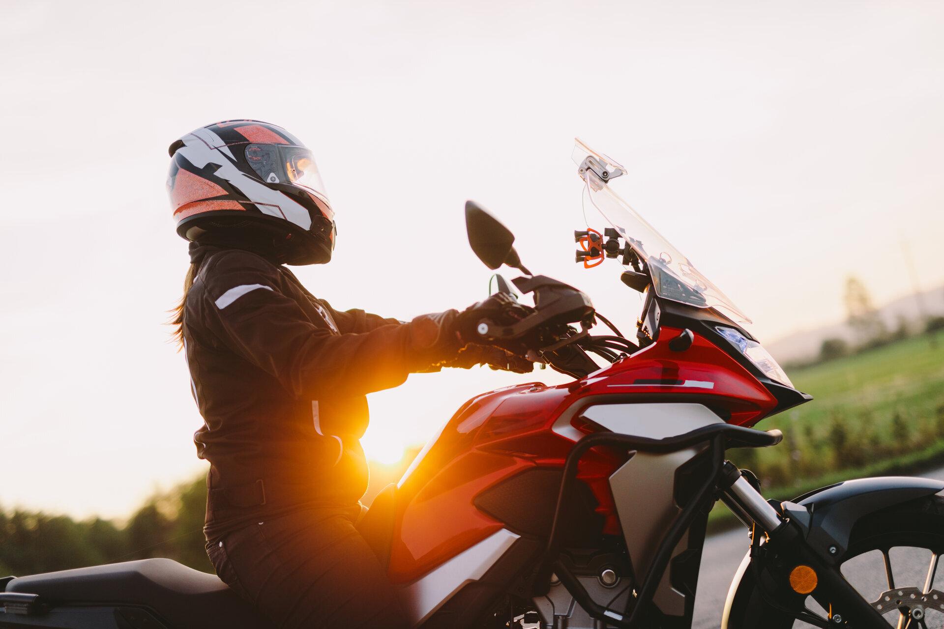 Frau, die bei Sonnenuntergang Motorrad fährt.